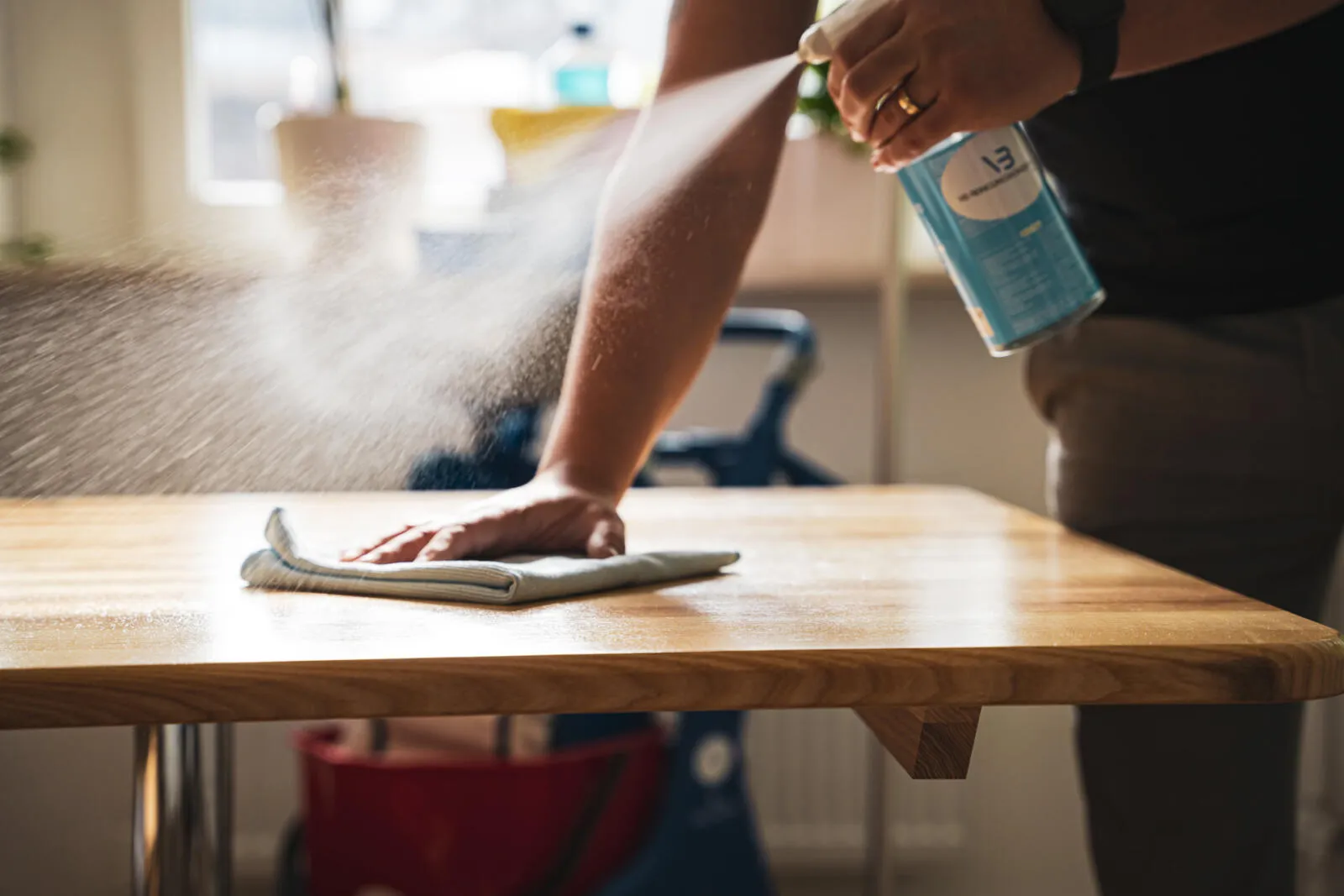 Tisch wird mit Reinigungsspray und Tuch gereinigt